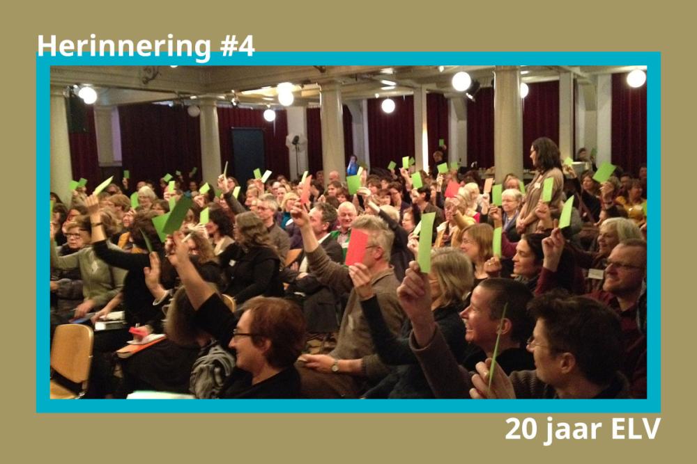 Foto van het publiek bij de vertaaldagen die rode en groene kaartjes omhoog houden.