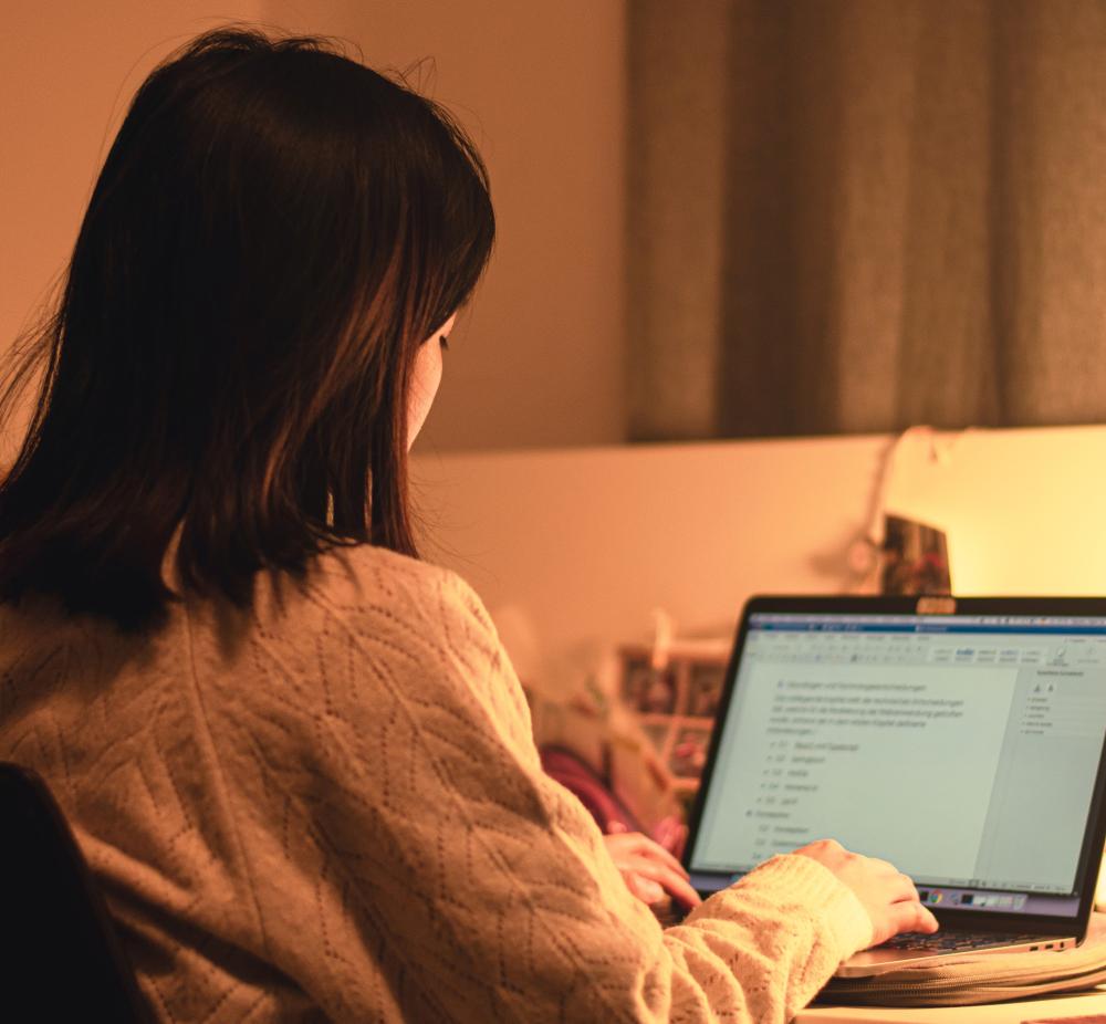 Foto van een jonge vrouw met Aziatisch uiterlijk achter een laptop.