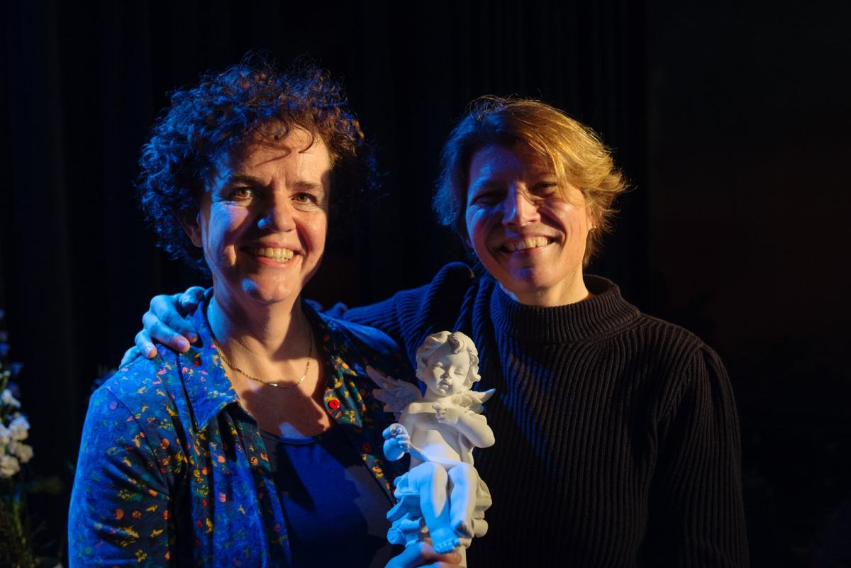 Foto van Nicolette Hoekmeijer en Hanneke Marttin, twee van de organisatoren van de Vertalersgeluktournee. Ze poseren met de Vertaalengel-trofee.
