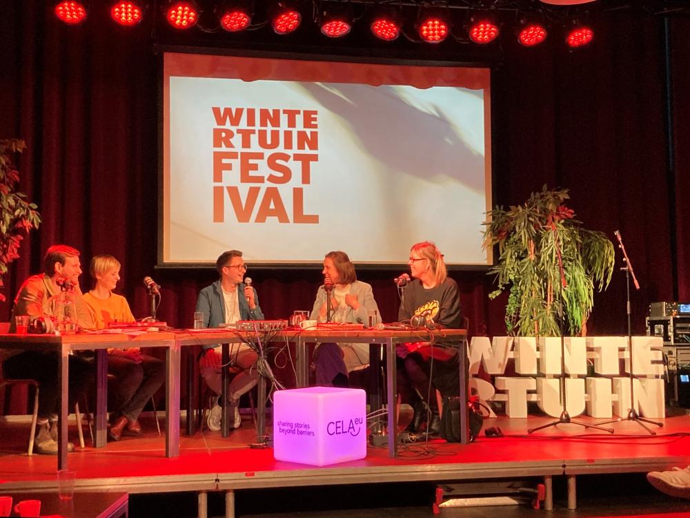 Vijf sprekers op het podium met op de achtergrond een projectiescherm met het logo van Wintertuinfestival.