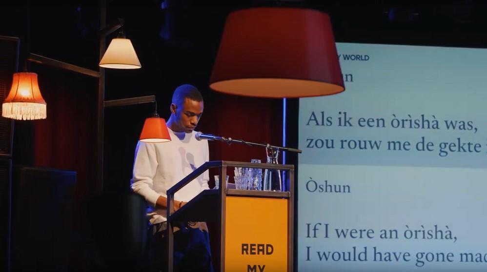Dichter en songwriter Logan February draagt een tekst voor die naast hen op een scherm staat geprojecteerd