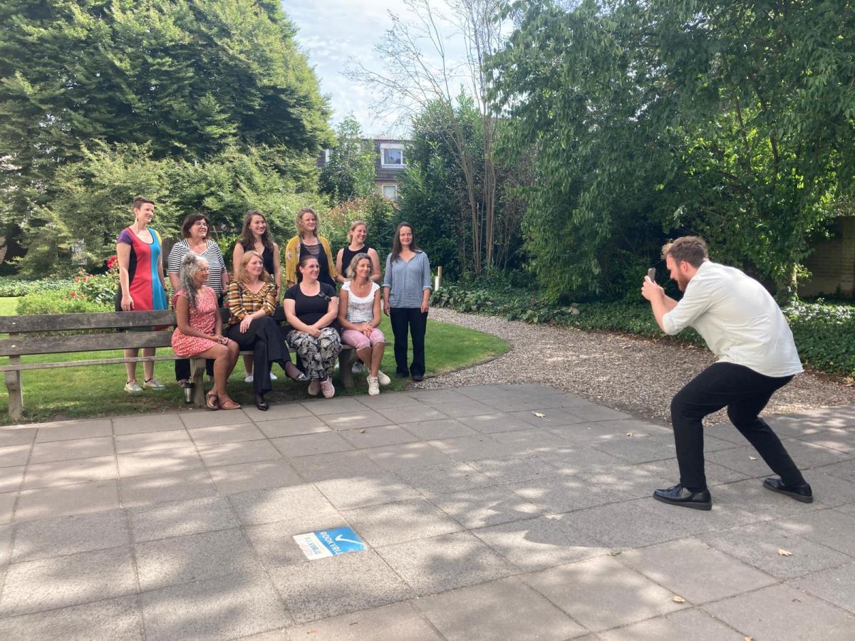 foto van jongen die een foto maakt van een groep cursisten en docenten in de binnentuin van de Universiteit Utrecht
